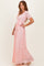 woman wearing a pink lace maxi dress with a tie waist and short sleeves