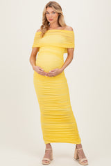 woman wearing a yellow off-the-shoulder maternity dress that hugs her baby bump with ruched detailing