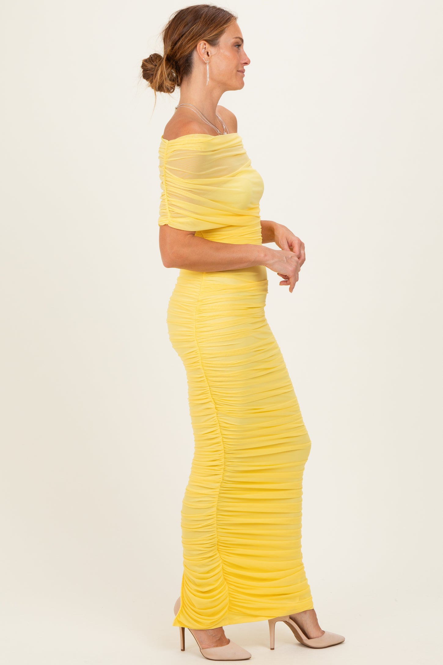 woman wearing a yellow off-the-shoulder ruched maxi dress with fitted silhouette and sheer details