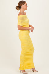 woman wearing a yellow off-the-shoulder ruched maxi dress with fitted silhouette and sheer details