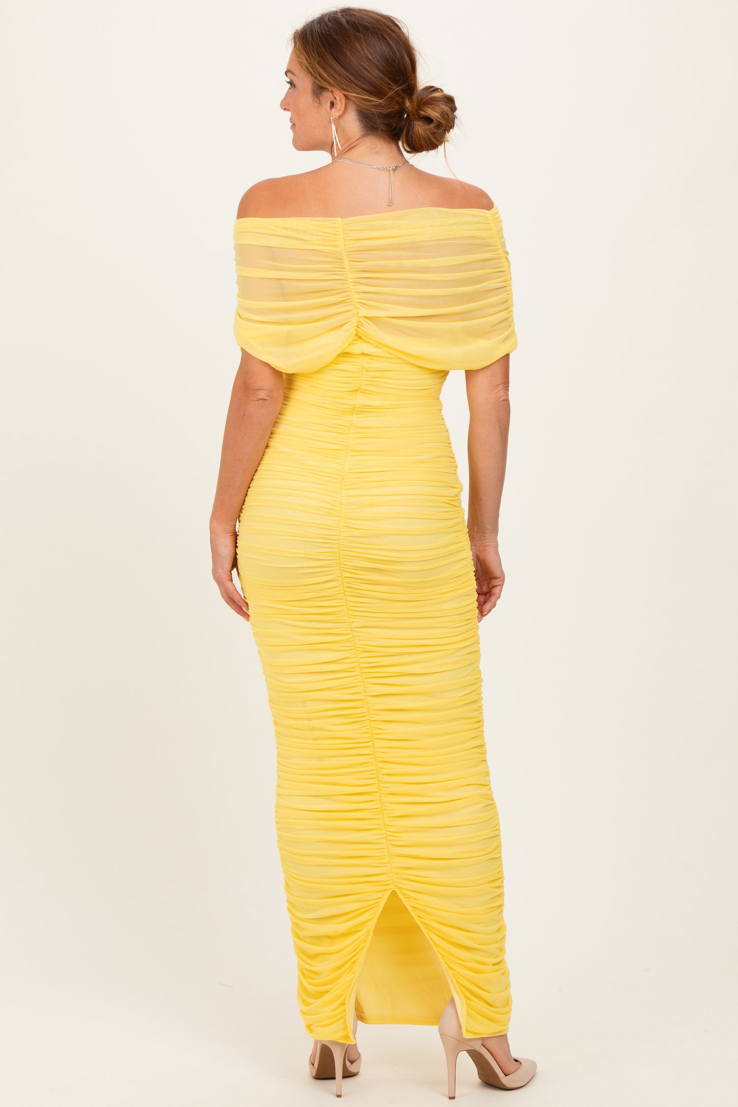 woman wearing a yellow off-shoulder ruched maxi dress with a back slit and fitted silhouette