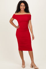 woman wearing a red off-the-shoulder bodycon dress with ruched detailing and a fitted silhouette