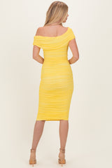 woman wearing a yellow off-shoulder bodycon dress with ruched detailing, viewed from the back