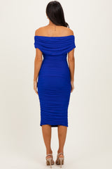 woman wearing a royal blue off-the-shoulder ruched midi dress, showing a fitted silhouette from the back