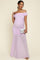 woman wearing a light purple off-shoulder maternity dress with ruching and a flowing skirt, holding a clutch and showing her baby bump