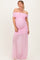woman wearing a light pink off-the-shoulder maternity gown with ruched detailing and sheer skirt, showcasing her baby bump