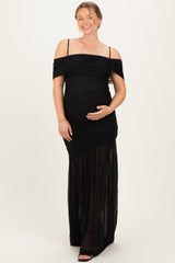 woman wearing a black off-the-shoulder maternity maxi dress, showing her baby bump and smiling