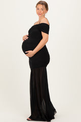 woman wearing a black off-the-shoulder maternity gown with ruched detailing and a flowing skirt, showing her baby bump