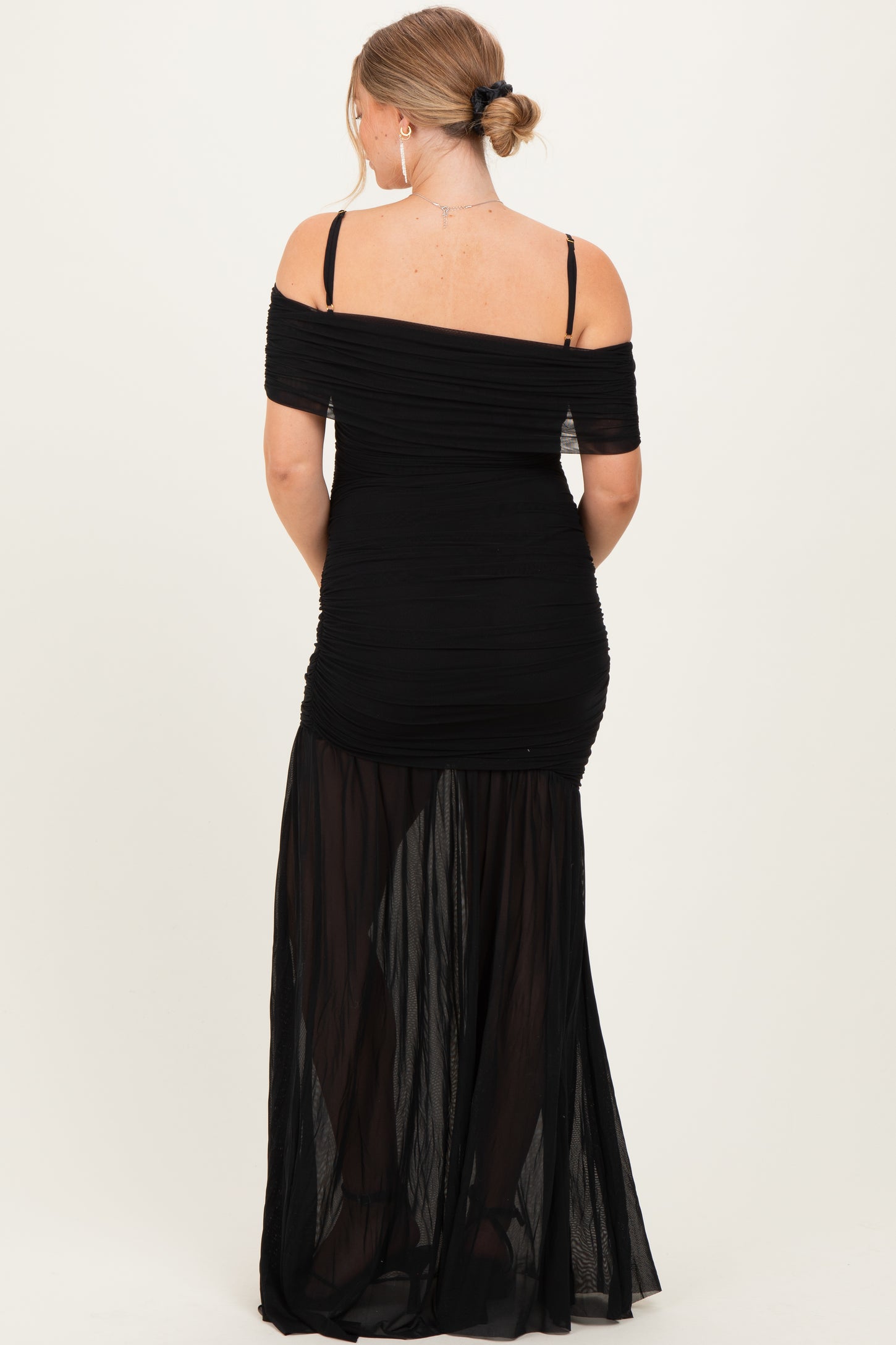 woman wearing a black off-the-shoulder maternity gown with ruched detailing and sheer bottom panels