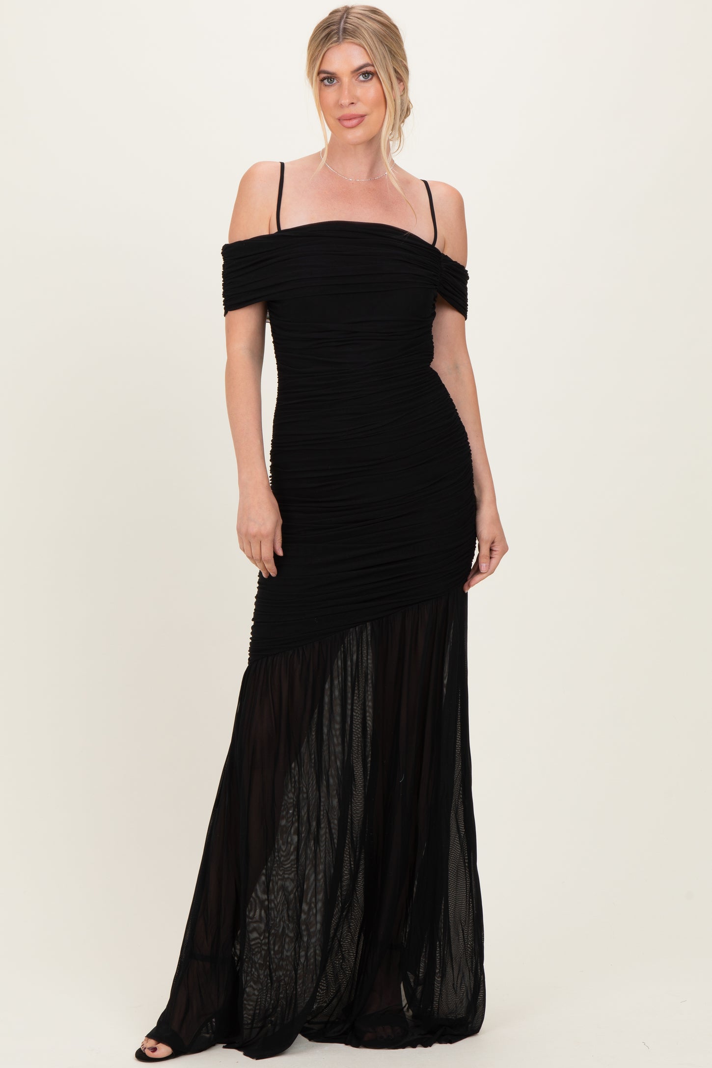woman wearing a black off-shoulder evening gown with ruched detailing and sheer bottom panel
