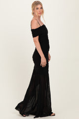 woman wearing a black off-the-shoulder evening gown with ruched detailing and a flowy skirt
