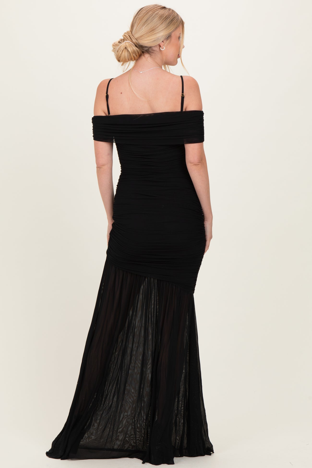 woman wearing a black off-the-shoulder fitted dress with ruching and a sheer maxi skirt