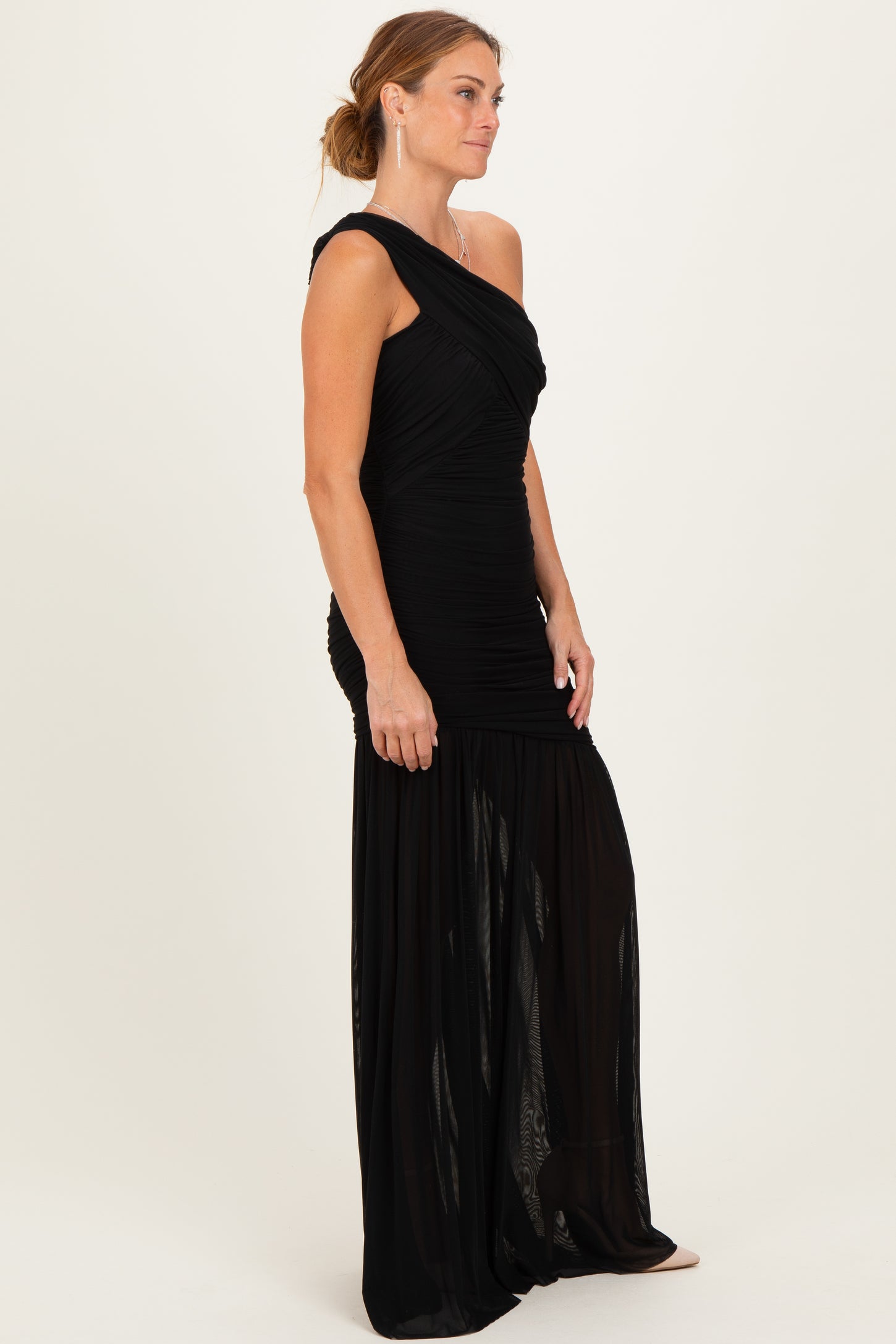 woman wearing a black one-shoulder evening gown with ruching and a flowing skirt