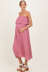 woman wearing a dusty pink strapless maternity dress with ruffle detail and holding her baby bump