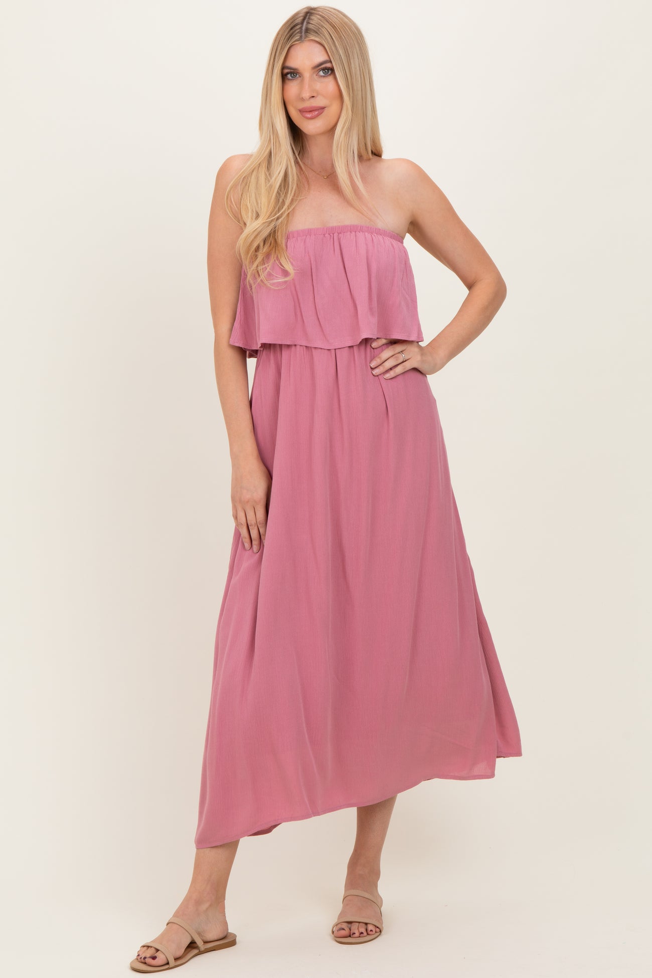 woman wearing a pink strapless maxi dress with a ruffled bodice and flowing skirt