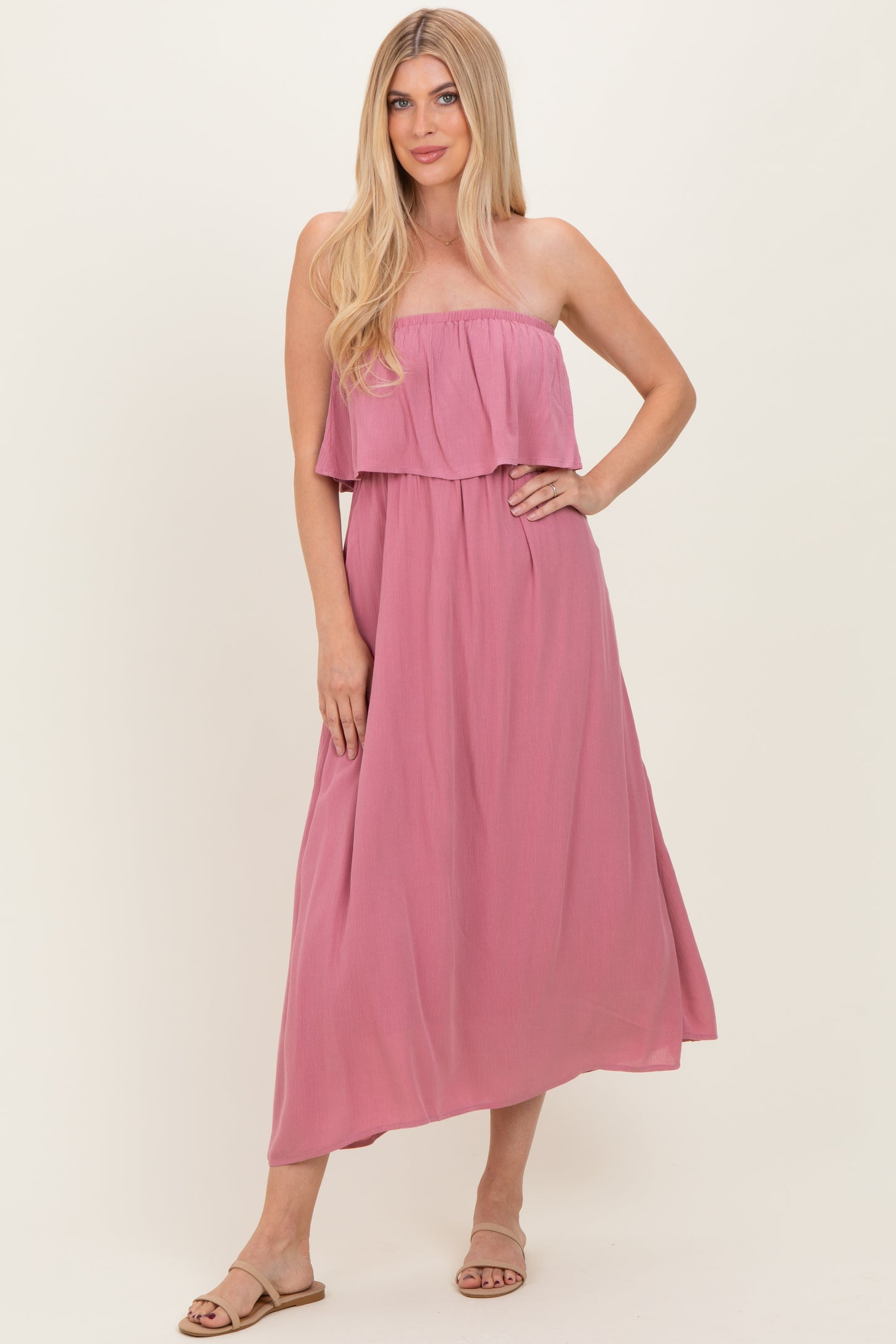 woman wearing a pink strapless maxi dress with a ruffled bodice and flowing skirt