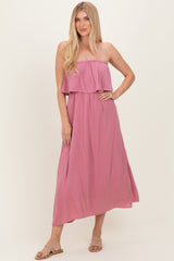 woman wearing a pink strapless maxi dress with a ruffled bodice and flowing skirt