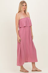 woman wearing a pink strapless maxi dress with ruffle detail, styled with sandals and long hair down