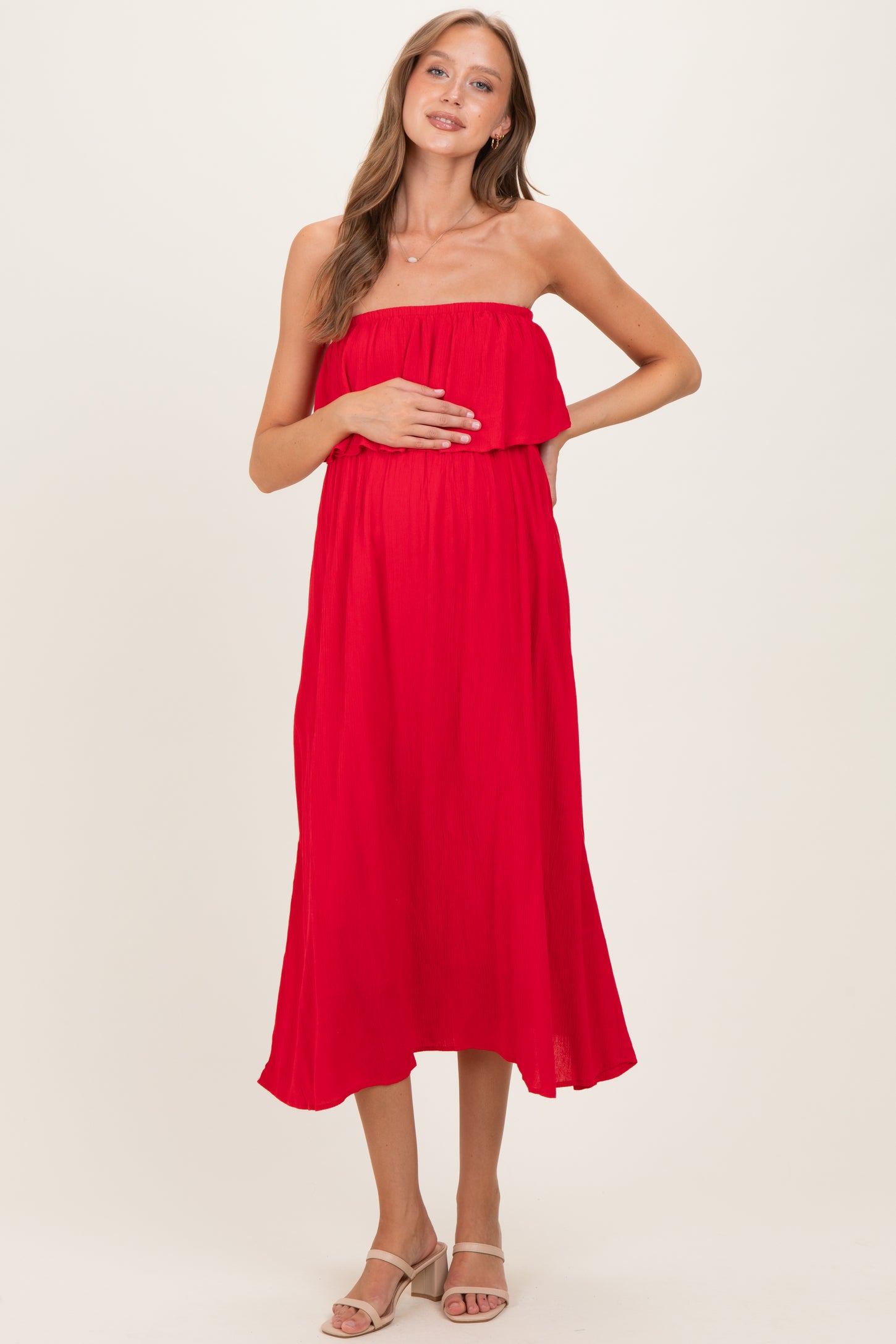 woman wearing a red strapless maternity dress with a gathered bodice and baby bump visible