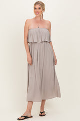 woman wearing a taupe strapless midi dress with a ruffled top and a relaxed fit, standing on a light background