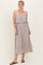 woman wearing a taupe strapless midi dress with a ruffled top and a relaxed fit, standing on a light background