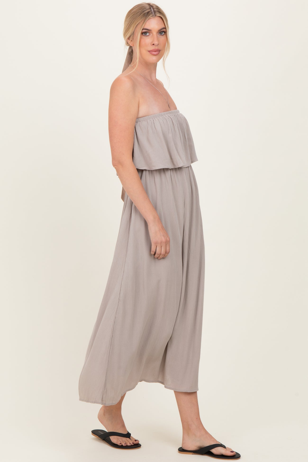 woman wearing a light gray strapless maxi dress with a flowing silhouette