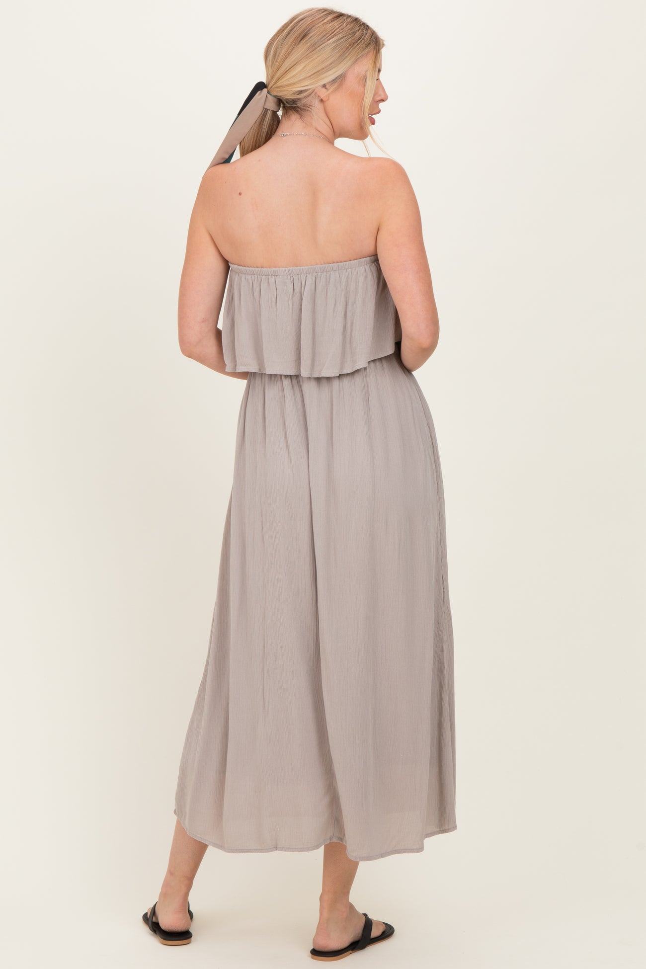 woman wearing a taupe strapless maxi dress with a layered ruffle detail and a flowing silhouette