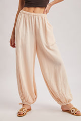 woman wearing light peach wide-leg pants with an elastic waistband and tapered ankles, styled with open-toe sandals