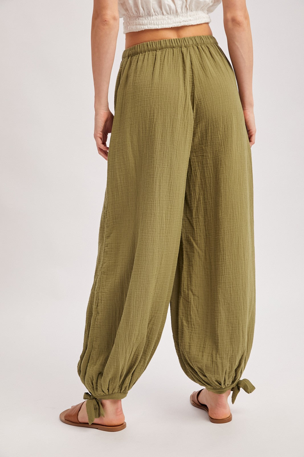 woman wearing olive green wide leg lounge pants with tie details at the ankles