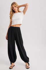 woman wearing a white cropped t-shirt and black flowy pants with a relaxed fit and a tied waistband
