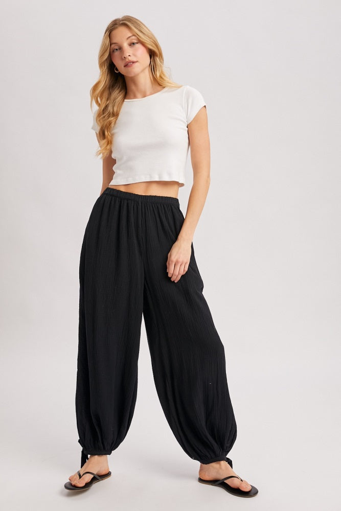 woman wearing a white cropped t-shirt and black pleated harem pants with a relaxed fit