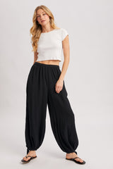 woman wearing a white cropped t-shirt and black pleated harem pants with a relaxed fit