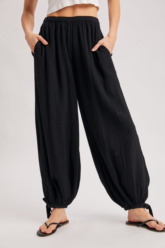 woman wearing black crinkle textured harem pants with a relaxed fit and side pockets