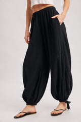 woman wearing black wide-leg pants with pockets and ankle ties, paired with a cropped top and sandals