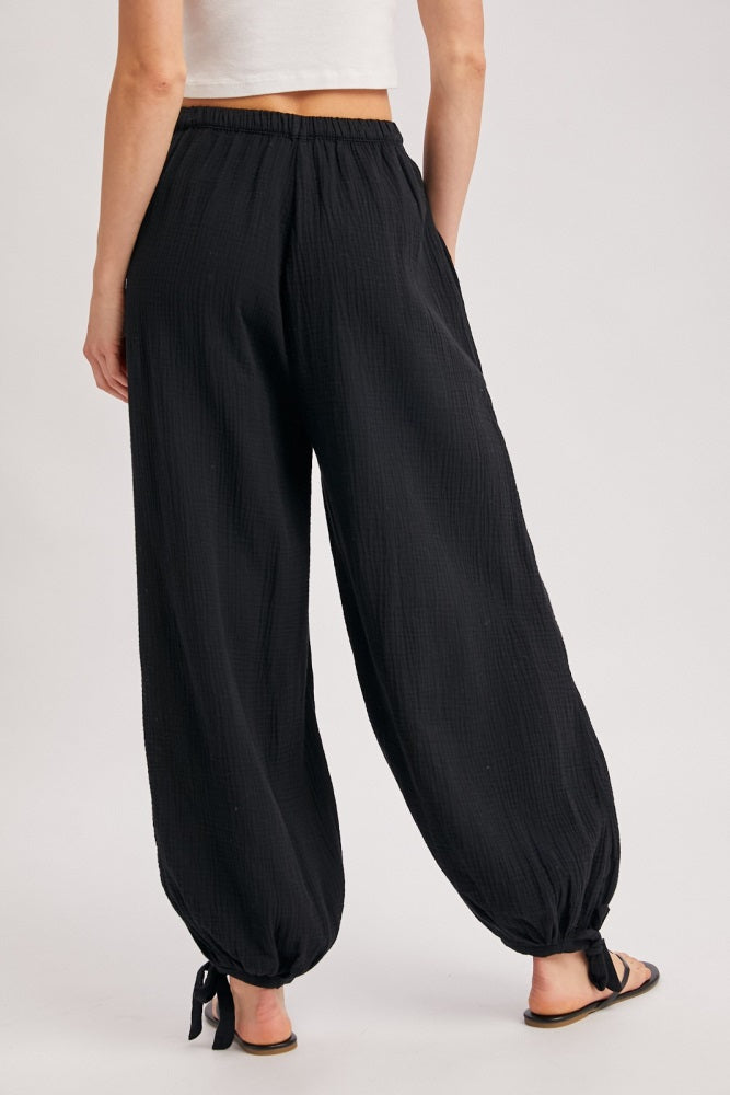 woman wearing black wide-leg pants with cinched ankles, styled with a cropped top, showing the back view