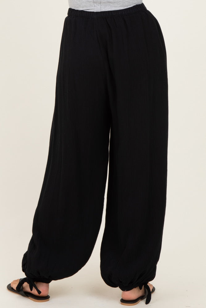 woman wearing black loose-fitting culottes with drawstring details at the hem and paired with flip-flops