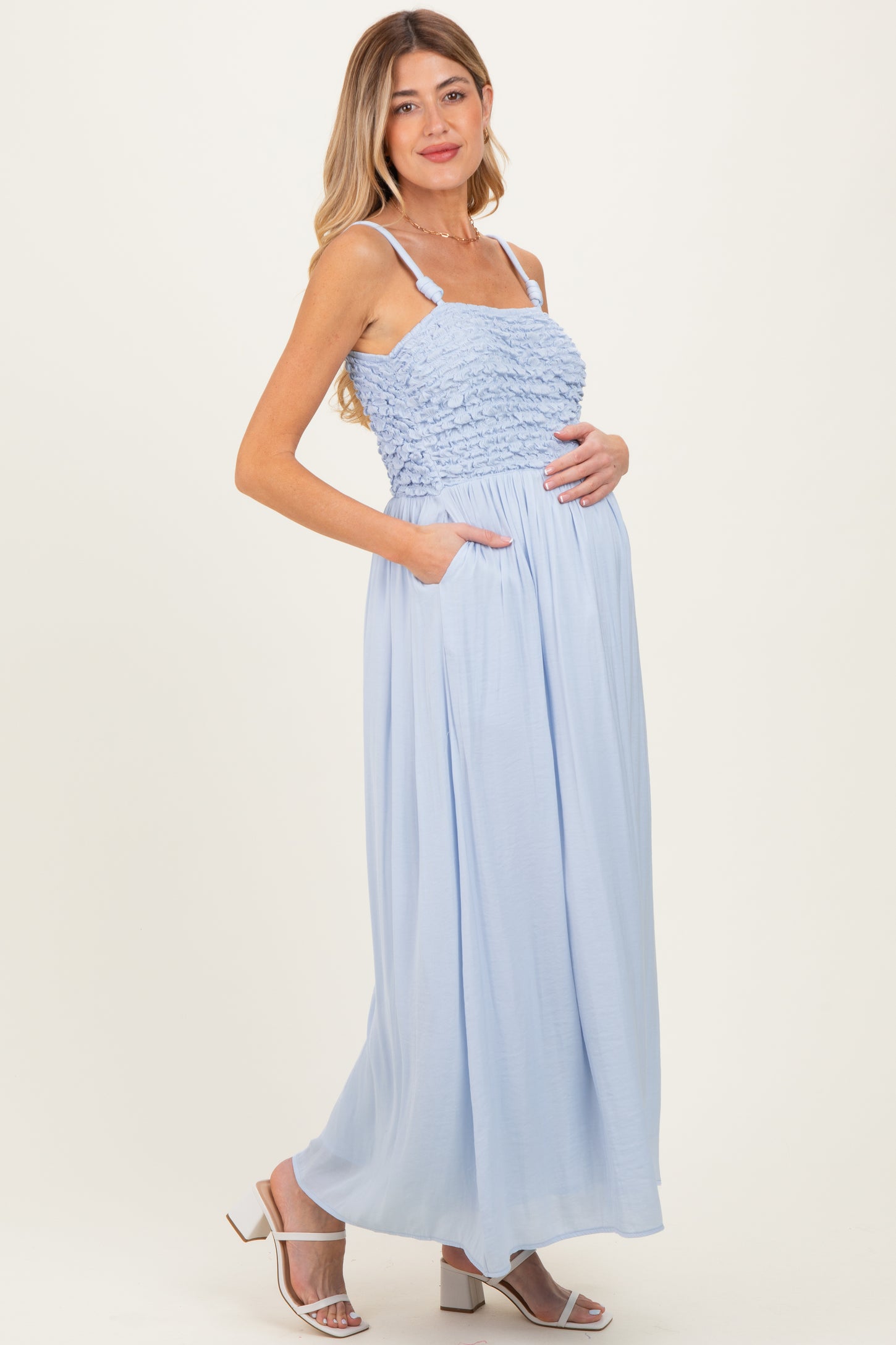 woman wearing a light blue maternity maxi dress with smocked bodice and pockets, showcasing her baby bump