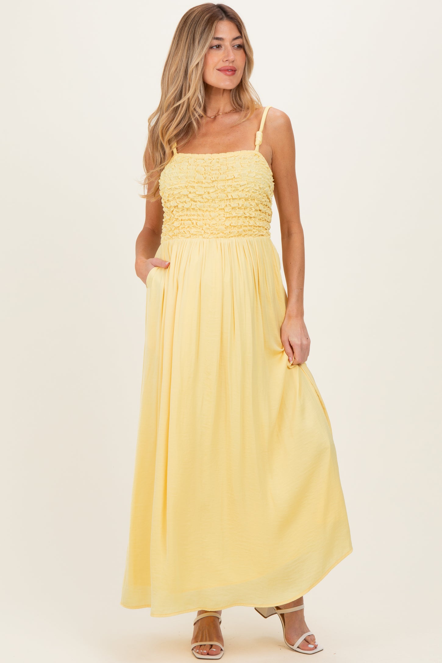 woman wearing a yellow maternity maxi dress with smocked bodice and pockets