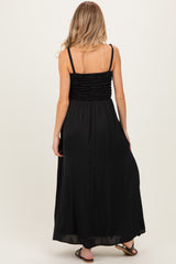 woman wearing a black maternity maxi dress with a smocked bodice and flowing skirt, showing her back