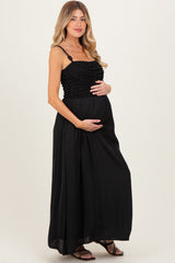 woman wearing a black maternity maxi dress with ruffled details and holding her baby bump