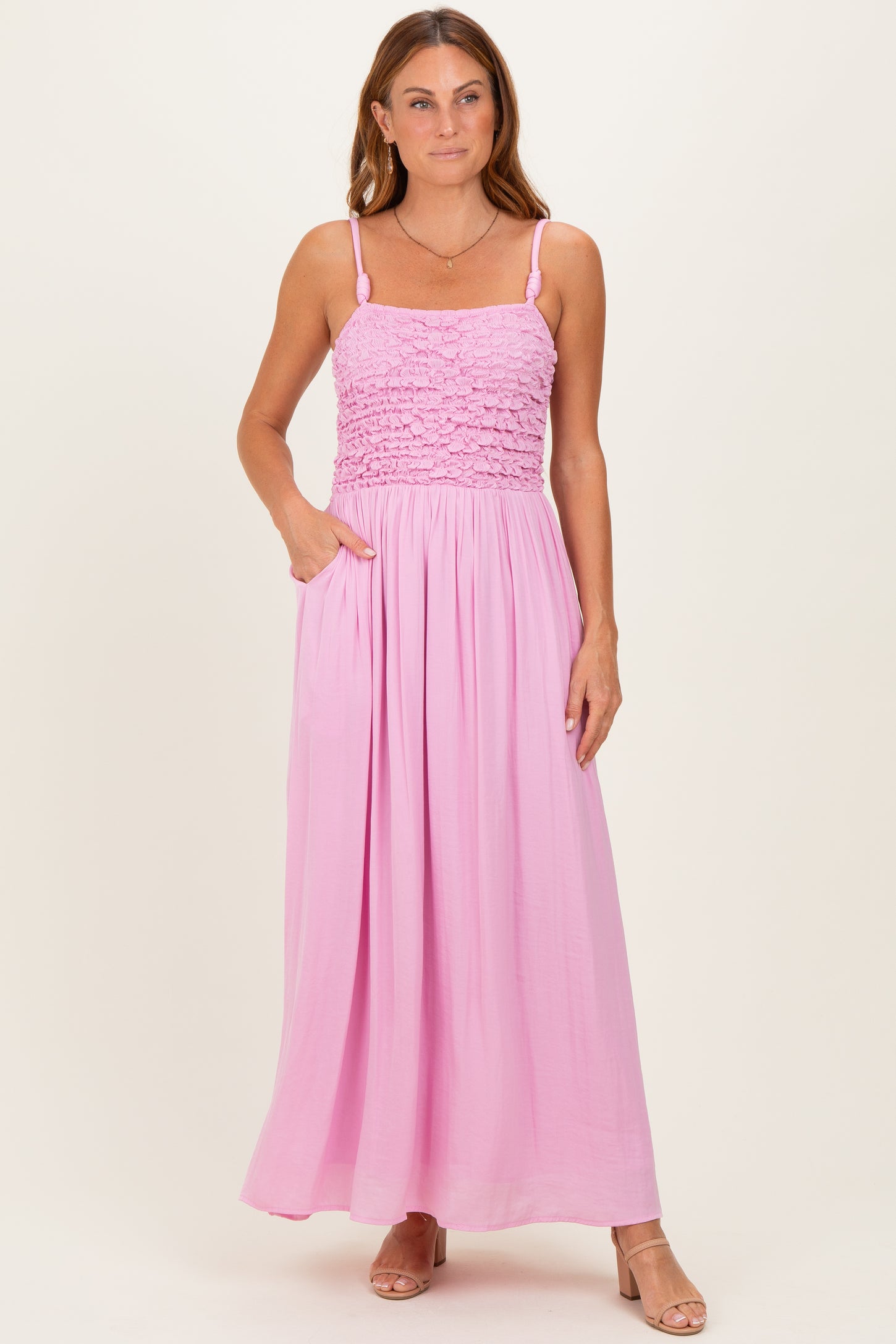 woman wearing a pink smocked maxi dress with adjustable straps and pockets