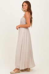 woman wearing a beige halter neck maxi dress with a smocked bodice and flowy skirt, standing sideways