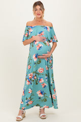 woman wearing a floral off-the-shoulder maternity maxi dress and cradling her baby bump
