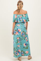 woman wearing a floral off-the-shoulder maternity maxi dress in turquoise with a flowy ruffle detail
