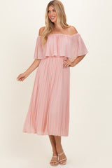 woman wearing a blush pink off-the-shoulder pleated maxi dress with a flowing silhouette