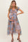woman wearing a floral print maternity dress with a flowy skirt and a baby bump visible, smiling and holding her belly