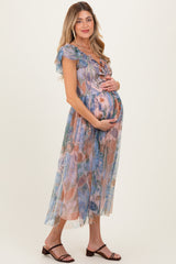 woman wearing a floral print maternity dress with ruffle sleeves, gently cradling her baby bump