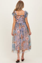 woman wearing a floral printed maternity dress with ruffled sleeves and a smocked bodice, showing a flowy tulle skirt from the back