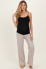woman wearing a black maternity tank top and light gray wide-leg pants, showing her baby bump