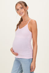 woman wearing a light pink maternity tank top and holding her baby bump